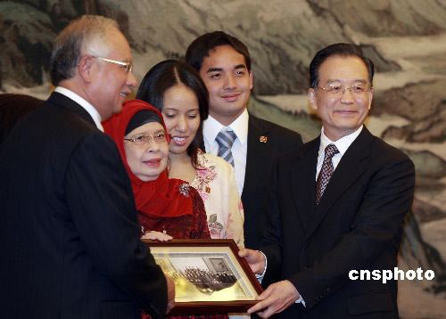 圖為溫家寶總理向馬來西亞總理納吉布一家贈(zèng)送一份特別的禮物：是在35年前，納吉布的父親、馬來西亞第二任總理拉扎克·侯賽因與中國總理周恩來在北京簽署兩國建交公報(bào)時(shí)的照片。中新社發(fā)盛佳鵬 攝