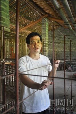 楊盛敏站在空置的兔籠前，兔籠是父母曾經(jīng)關他的鐵籠改造的。攝影閆小青。