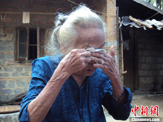 日本“海南島近代史研究會”創(chuàng)始人佐藤正人第22次到海南島調(diào)查日本侵瓊史。圖為在保亭黎族苗族自治縣南林鄉(xiāng)羅葵村，金靜美握著86歲老人林亞金的手。中新社發(fā) 張茜翼 攝