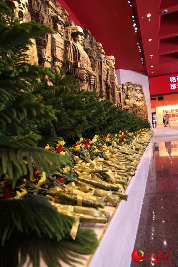 紀(jì)念館門廳的《銅墻鐵壁》雕塑墻，和人們獻(xiàn)上的花。邱越攝